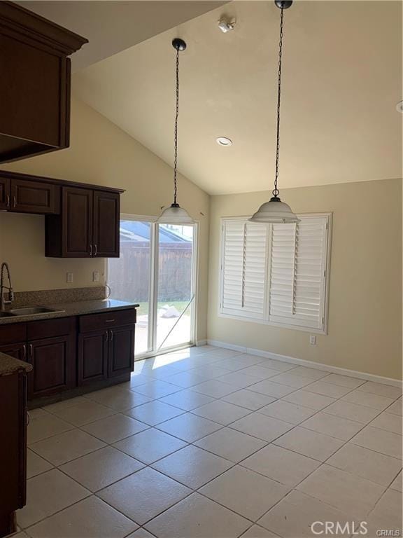 kitchen featuring sink, dark brown cabinets, hanging light fixtures, and light tile patterned flooring