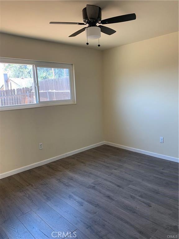 empty room featuring dark wood-type flooring and ceiling fan