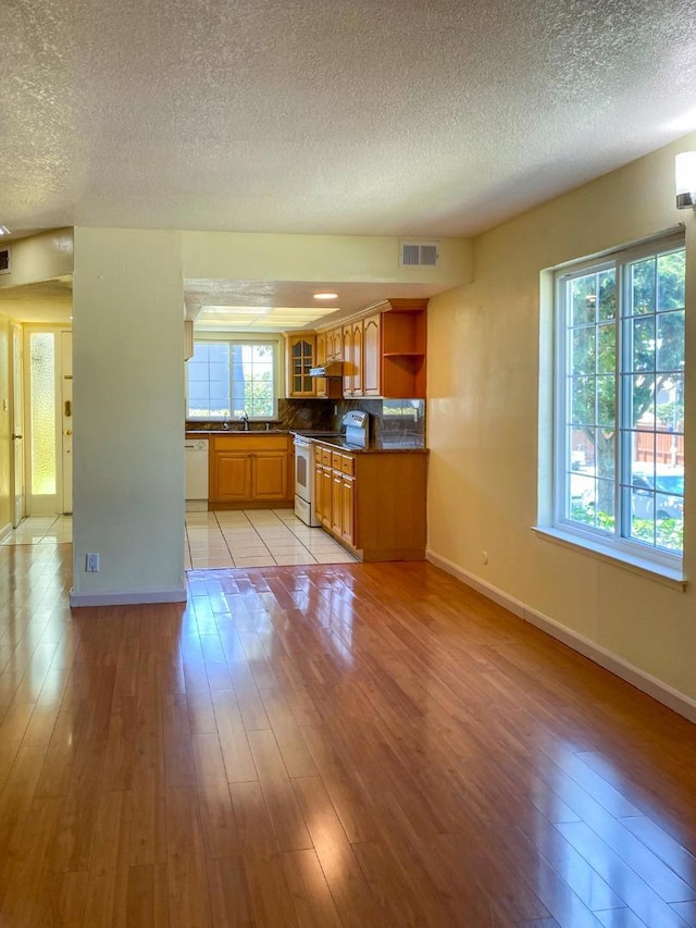 kitchen with tasteful backsplash, light wood-type flooring, sink, and white appliances