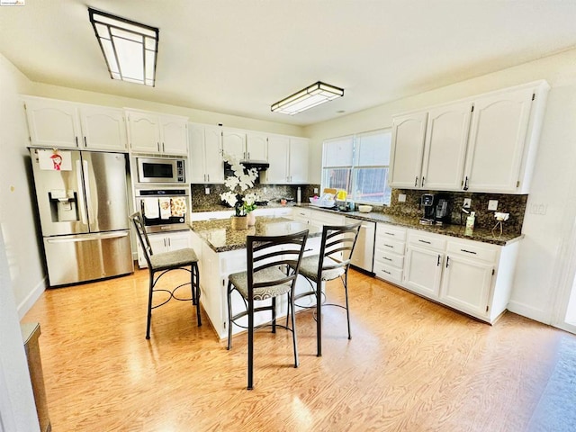 kitchen with dark stone countertops, white cabinetry, a breakfast bar, and appliances with stainless steel finishes