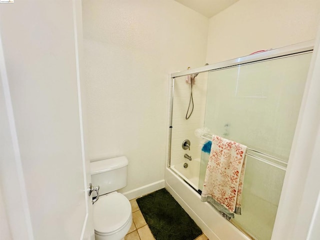 bathroom featuring tile patterned flooring, toilet, and bath / shower combo with glass door