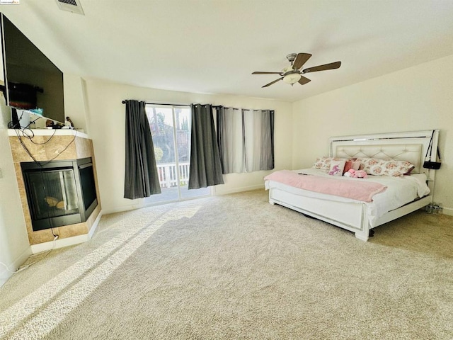 bedroom with carpet flooring, access to outside, ceiling fan, and a tiled fireplace