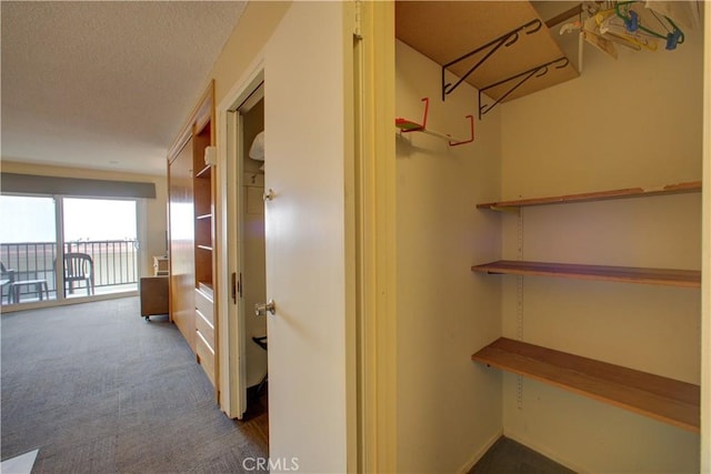 corridor with a textured ceiling and carpet floors