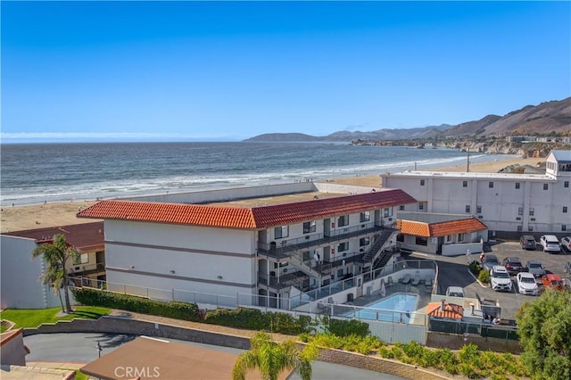 drone / aerial view with a water and mountain view and a view of the beach