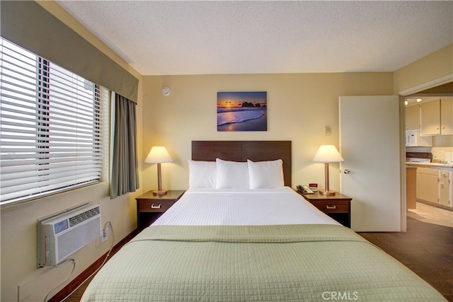 bedroom with dark carpet, a textured ceiling, a wall mounted AC, and ensuite bath