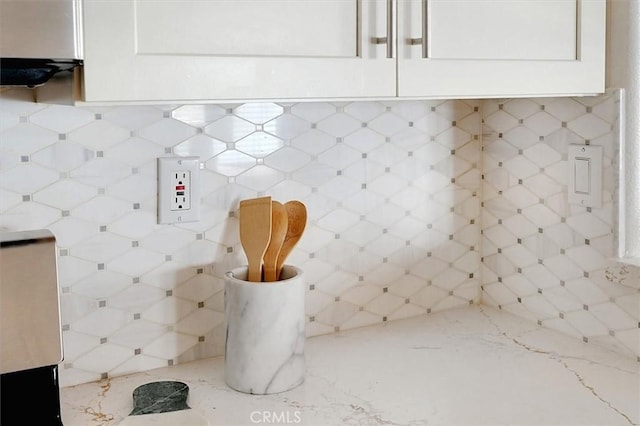 room details with light stone countertops, white cabinetry, and tasteful backsplash