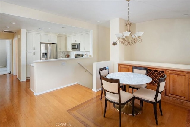 dining space with light wood-type flooring and an inviting chandelier