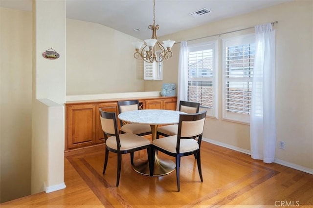 dining room featuring lofted ceiling, an inviting chandelier, and light hardwood / wood-style floors