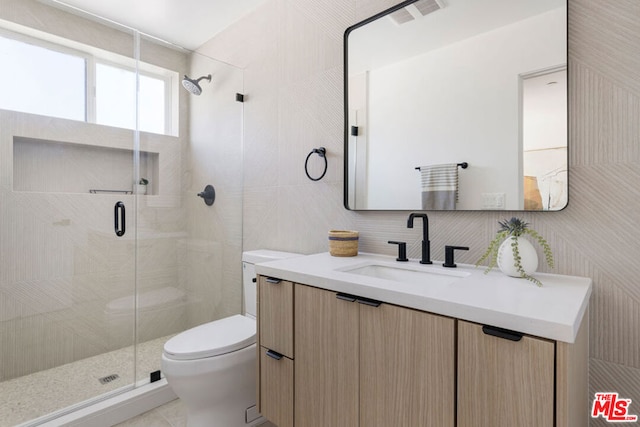 bathroom with backsplash, toilet, a shower with door, vanity, and tile walls