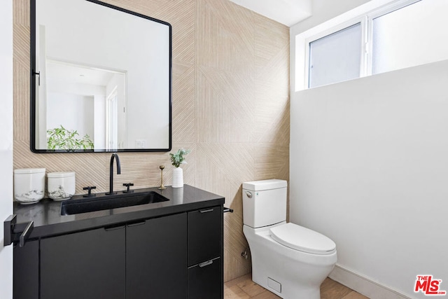 bathroom with vanity, toilet, and tile walls