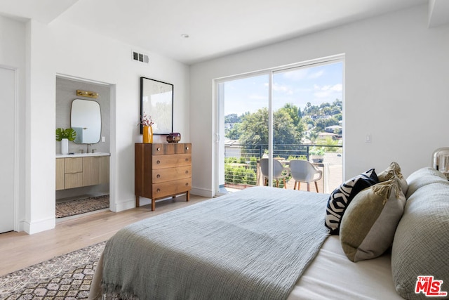 bedroom featuring ensuite bathroom and light hardwood / wood-style flooring