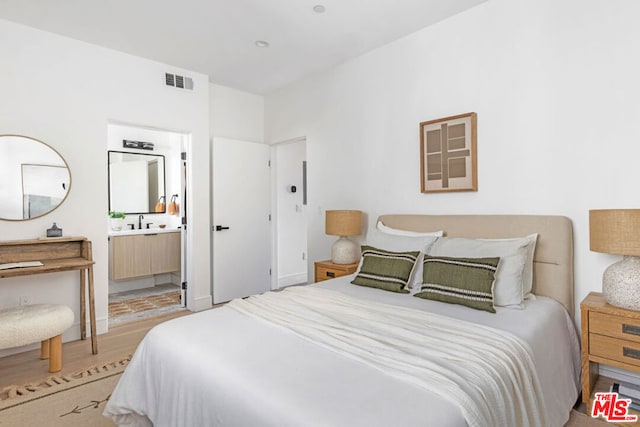 bedroom featuring ensuite bath, sink, and light hardwood / wood-style flooring