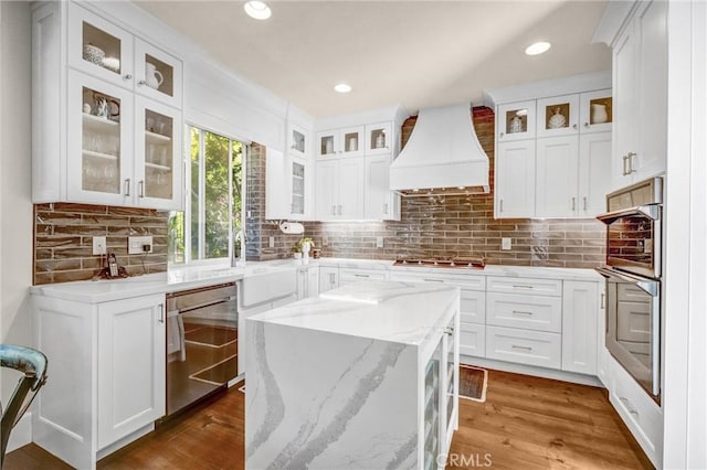 kitchen with premium range hood, light stone counters, and white cabinets