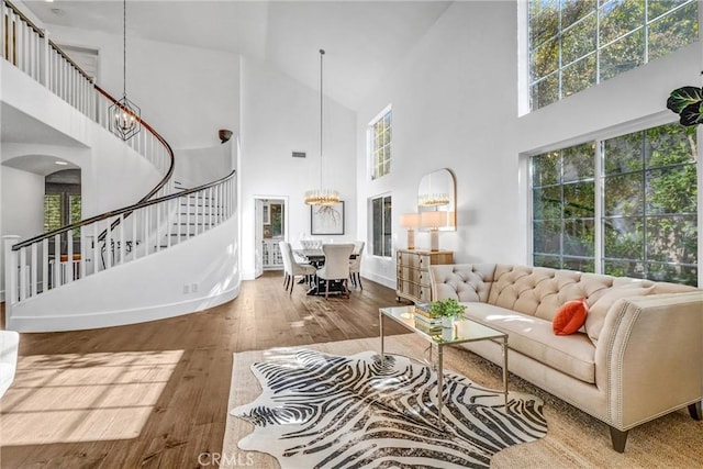 living room featuring hardwood / wood-style flooring, a chandelier, a towering ceiling, and plenty of natural light