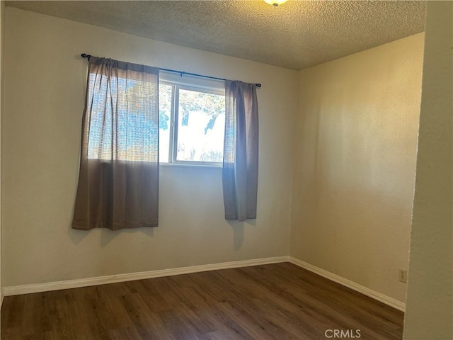 empty room with dark hardwood / wood-style floors and a textured ceiling