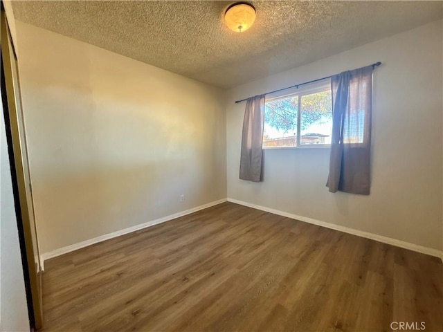 spare room with a textured ceiling and dark hardwood / wood-style floors