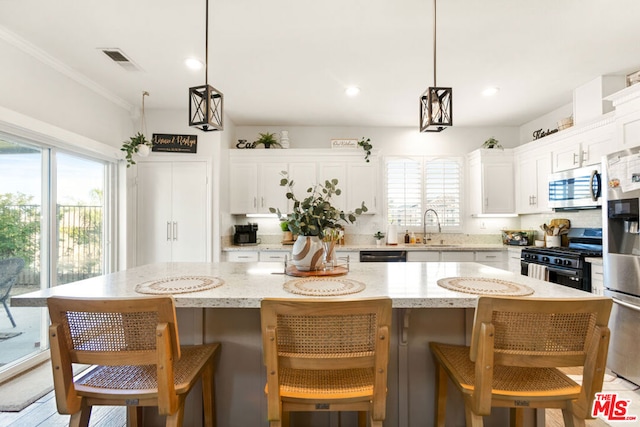 kitchen with pendant lighting, a center island, stainless steel appliances, and a wealth of natural light