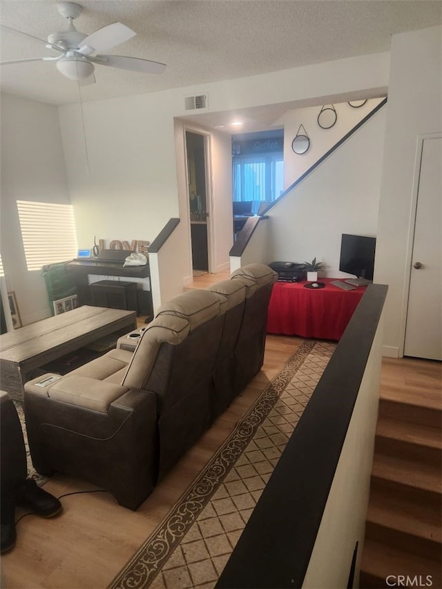 living room with ceiling fan, wood-type flooring, and a textured ceiling