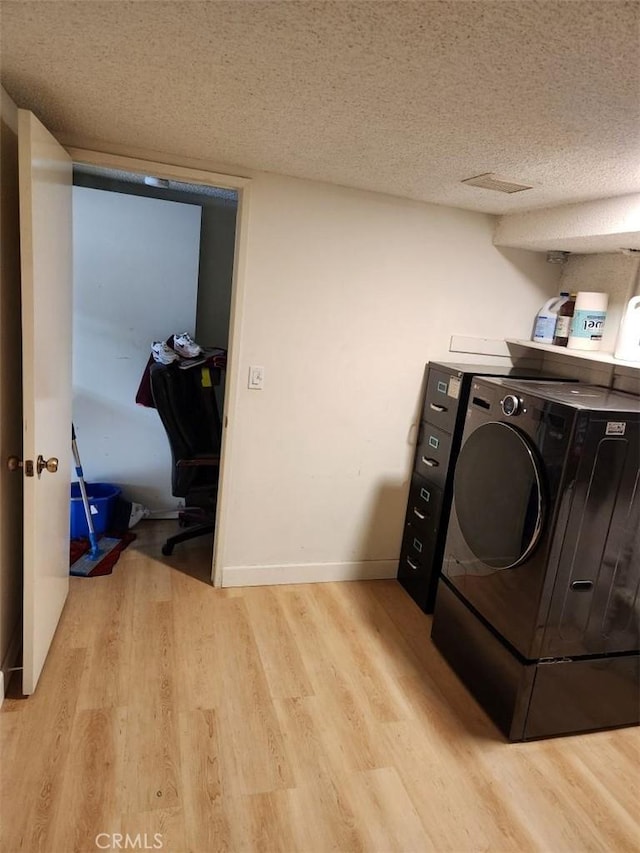 laundry room featuring washer / clothes dryer, a textured ceiling, and light wood-type flooring