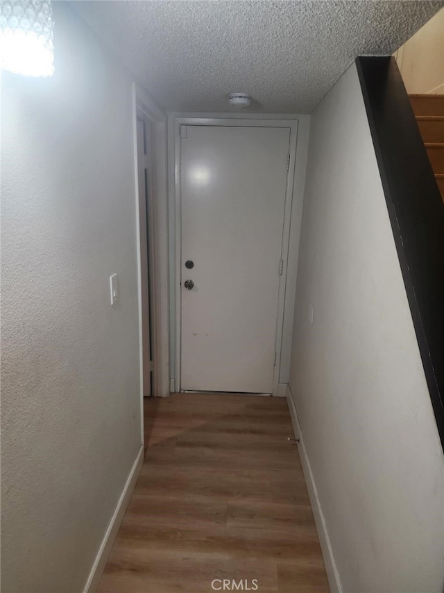 hall featuring wood-type flooring and a textured ceiling