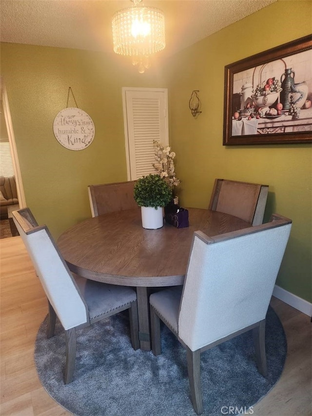 dining space featuring a chandelier, wood-type flooring, and a textured ceiling