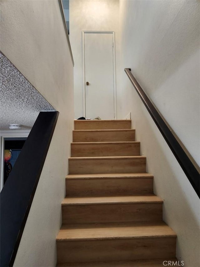 staircase with a textured ceiling