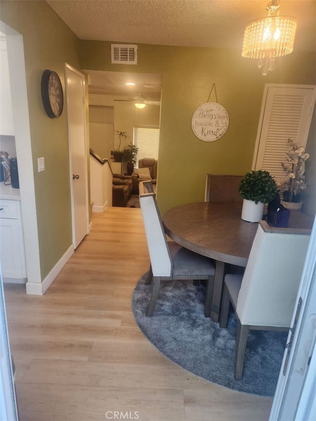 dining room featuring an inviting chandelier, a textured ceiling, and light wood-type flooring