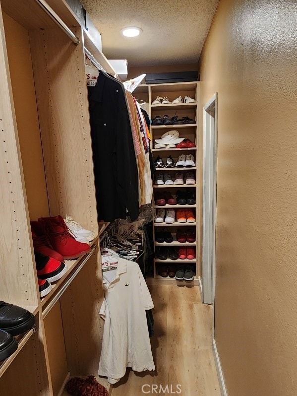 walk in closet with light hardwood / wood-style flooring