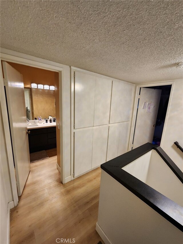 hallway with a textured ceiling and light wood-type flooring