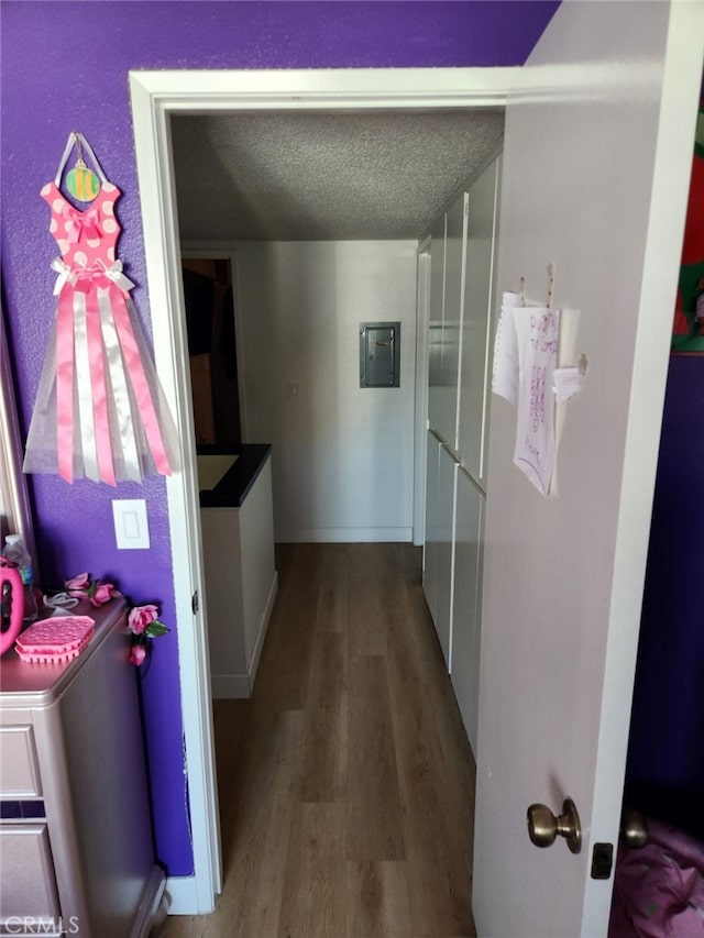 hall featuring a textured ceiling, hardwood / wood-style flooring, and electric panel