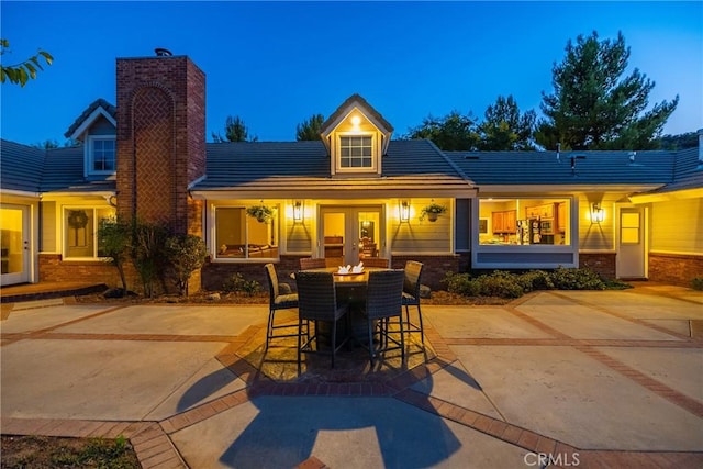 back house at dusk featuring a patio and french doors