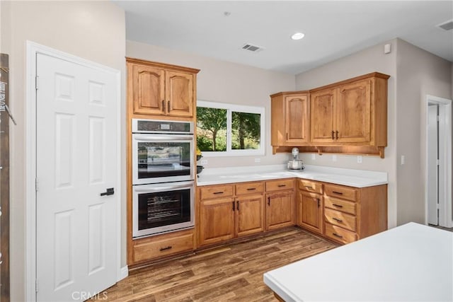 kitchen featuring stainless steel double oven and dark wood-type flooring