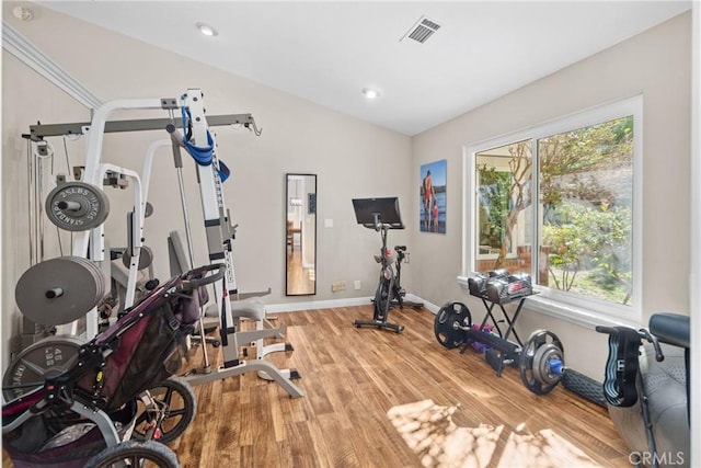 exercise area featuring hardwood / wood-style flooring, vaulted ceiling, and a healthy amount of sunlight