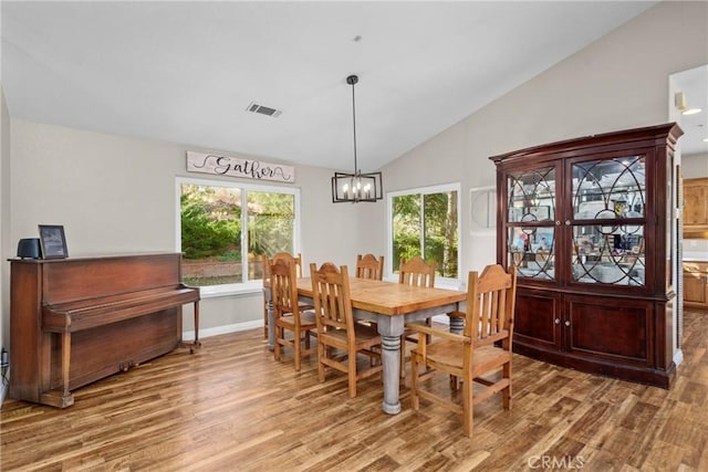 dining area with light hardwood / wood-style floors, vaulted ceiling, and a notable chandelier