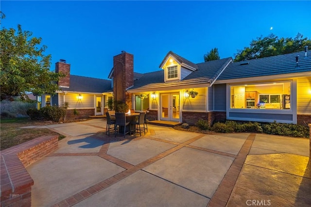 back house at dusk featuring a patio area and french doors