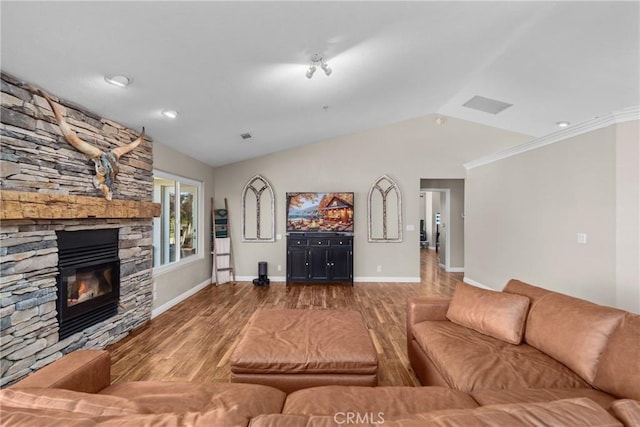 living room with a stone fireplace, crown molding, hardwood / wood-style floors, and vaulted ceiling