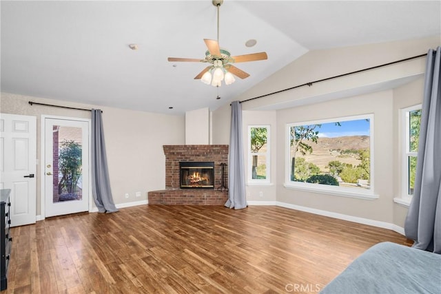 unfurnished living room with a brick fireplace, ceiling fan, wood-type flooring, and vaulted ceiling