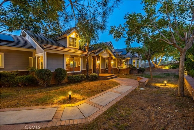 view of front of property with a front lawn, a porch, and solar panels