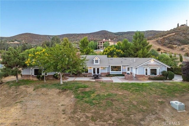 back of property featuring a mountain view, a yard, and a patio