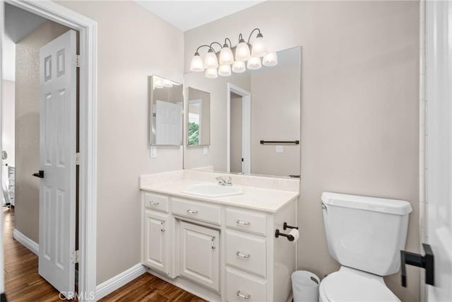 bathroom with wood-type flooring, vanity, and toilet