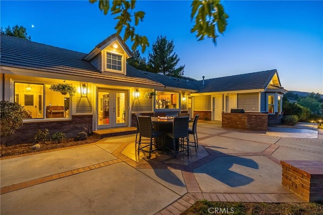 back house at dusk featuring area for grilling, a patio, and french doors