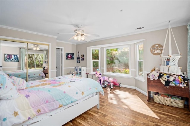 bedroom with hardwood / wood-style floors, ceiling fan, ornamental molding, and multiple windows