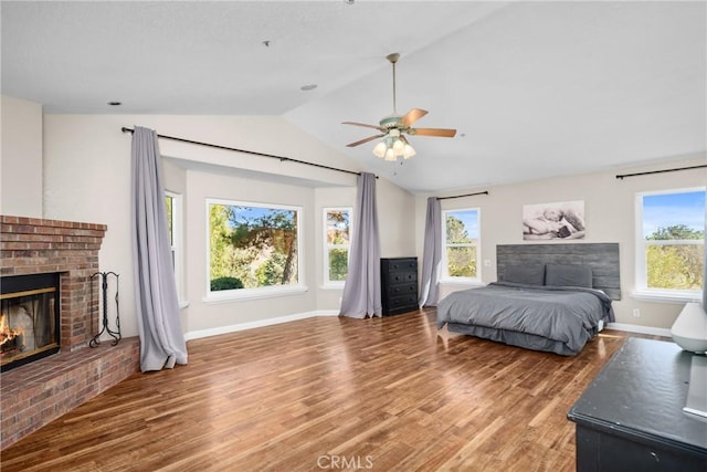 bedroom with hardwood / wood-style floors, ceiling fan, lofted ceiling, and a brick fireplace