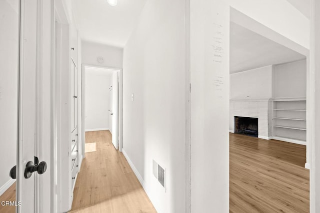 corridor with built in shelves and light wood-type flooring