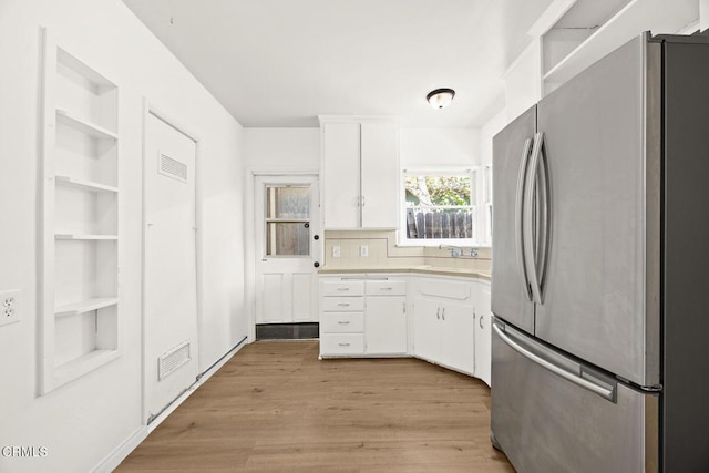 kitchen featuring stainless steel fridge, white cabinetry, and light hardwood / wood-style flooring