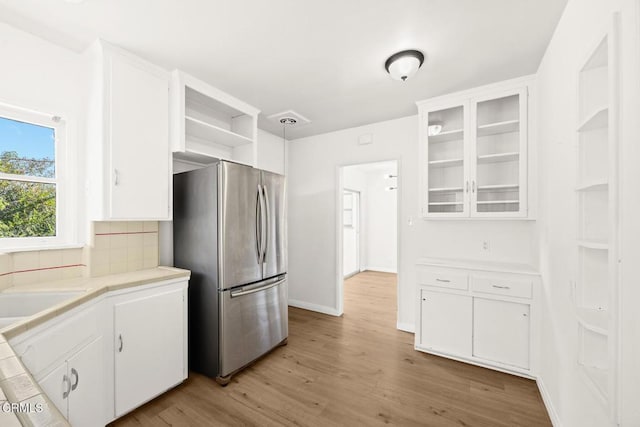 kitchen featuring light hardwood / wood-style flooring, decorative backsplash, decorative light fixtures, white cabinetry, and stainless steel refrigerator