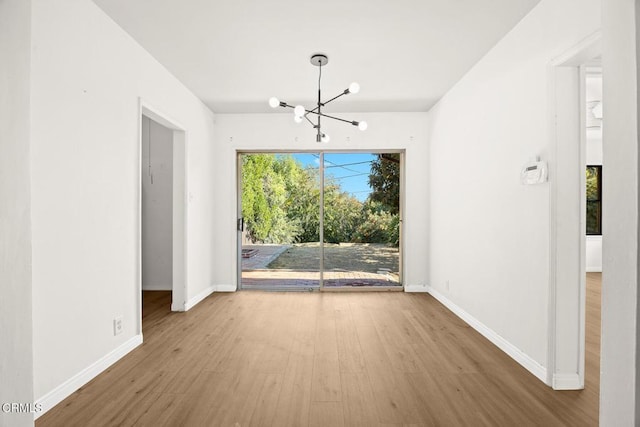 unfurnished dining area featuring hardwood / wood-style flooring and an inviting chandelier