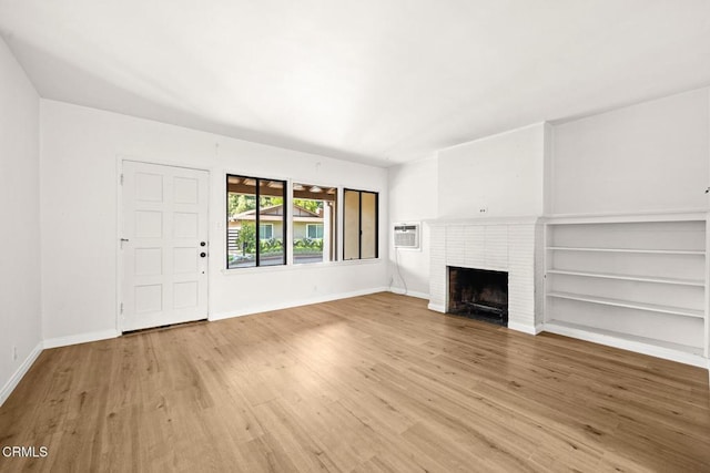 unfurnished living room featuring light hardwood / wood-style floors, an AC wall unit, and a fireplace