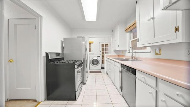 kitchen featuring sink, appliances with stainless steel finishes, light tile patterned flooring, washer / dryer, and white cabinetry