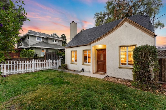 back house at dusk featuring a yard